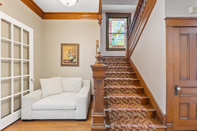 stairway with wood-type flooring and ornamental molding