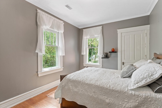 bedroom with wood-type flooring and crown molding