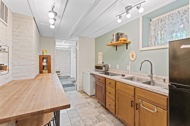 kitchen with brick wall, sink, and black appliances