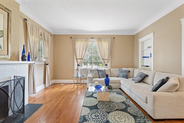 living room with hardwood / wood-style flooring, built in shelves, a fireplace, and crown molding