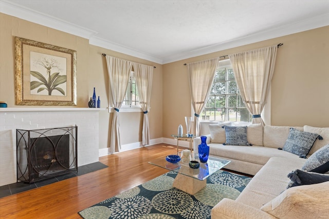 living room featuring a wealth of natural light, ornamental molding, wood-type flooring, and a brick fireplace