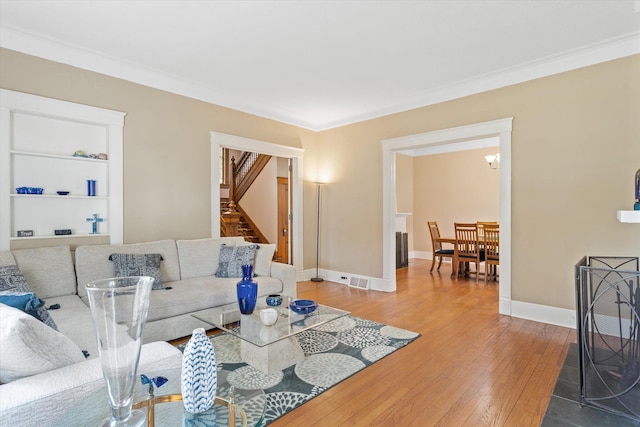 living room featuring wood-type flooring and crown molding