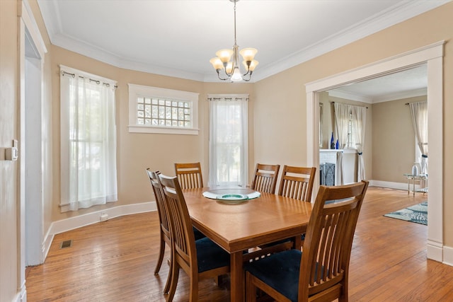 dining area with light wood-type flooring, crown molding, and a notable chandelier