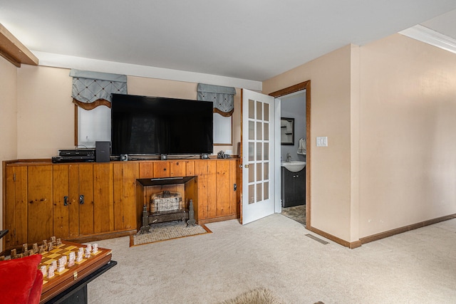 carpeted living room featuring crown molding, a wood stove, and sink