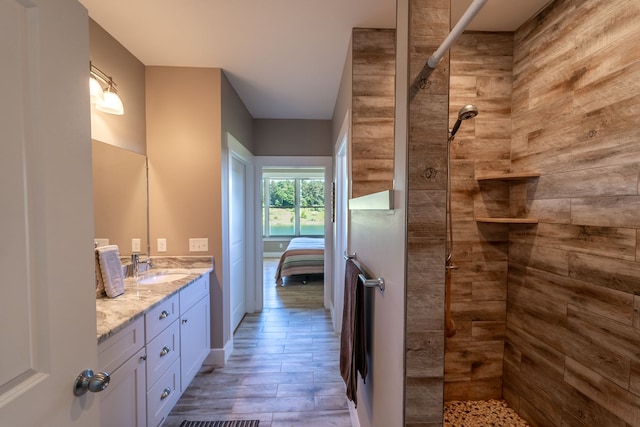 bathroom featuring hardwood / wood-style flooring, vanity, and a tile shower