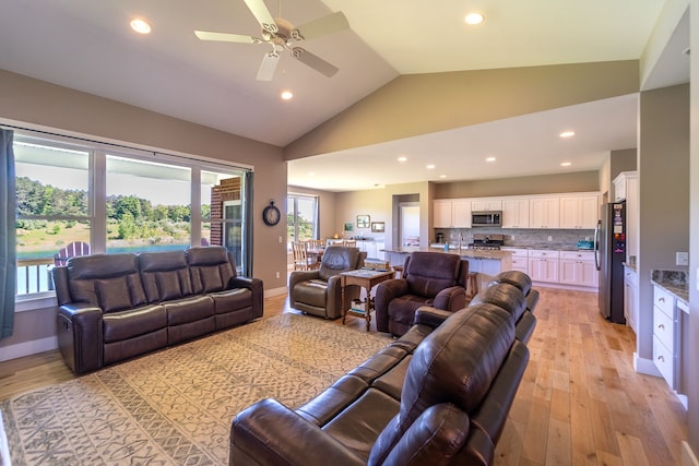 living room with ceiling fan, light hardwood / wood-style flooring, high vaulted ceiling, and a healthy amount of sunlight