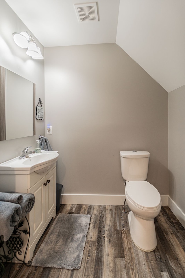 bathroom featuring vanity, hardwood / wood-style flooring, toilet, and lofted ceiling