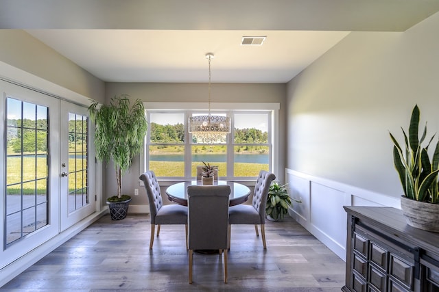 dining space featuring french doors, a water view, a wealth of natural light, and dark wood-type flooring