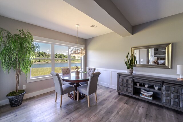 829 N Van Dyke Rd, Imlay City, MI 48444 - dining area with a chandelier, a wainscoted wall, wood finished floors, a water view, and a decorative wall