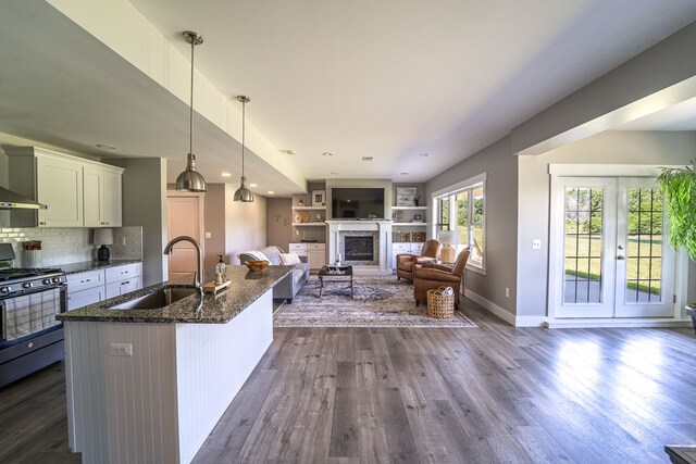 829 N Van Dyke Rd, Imlay City, MI 48444 - kitchen with a sink, stainless steel gas range oven, a glass covered fireplace, dark stone counters, and dark wood-type flooring