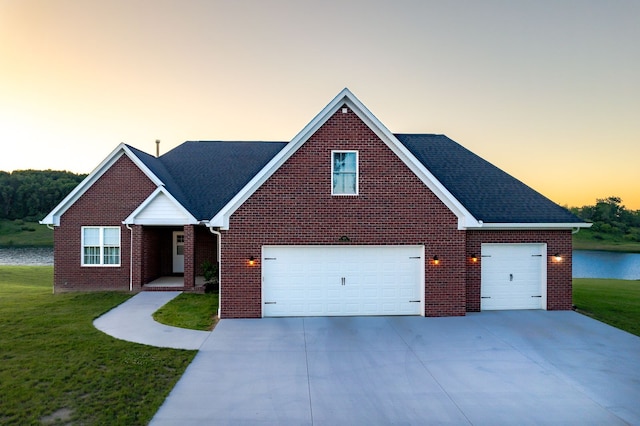 view of front of house with a garage, a yard, and a water view