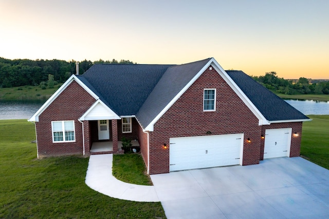 view of front of house featuring a yard, a water view, and a garage