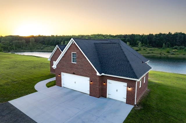 view of front of home with a lawn, a water view, and a garage