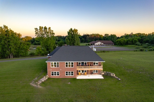 back house at dusk featuring a yard, a patio area, and a wooden deck