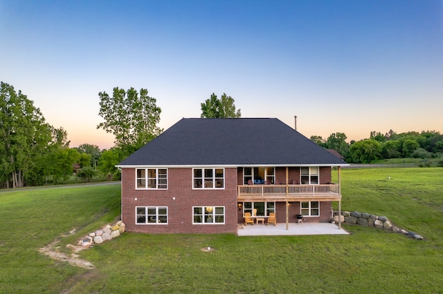 back house at dusk with a yard, a patio, and a wooden deck