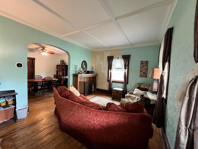 living room featuring hardwood / wood-style floors, ceiling fan, crown molding, and coffered ceiling