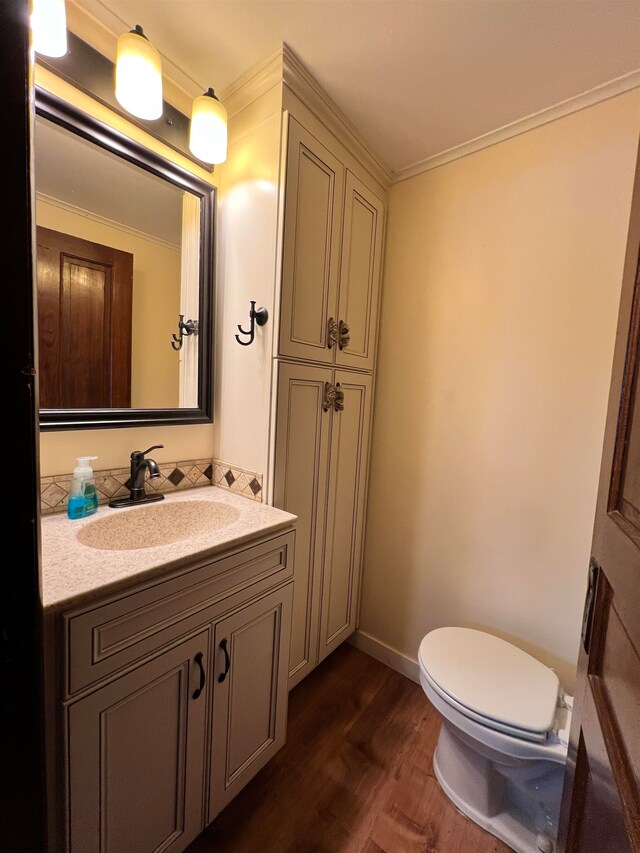 bathroom with vanity, toilet, wood-type flooring, and crown molding