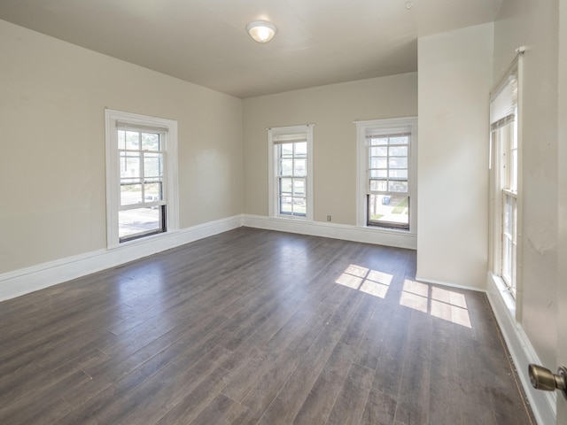 empty room with plenty of natural light and dark hardwood / wood-style flooring