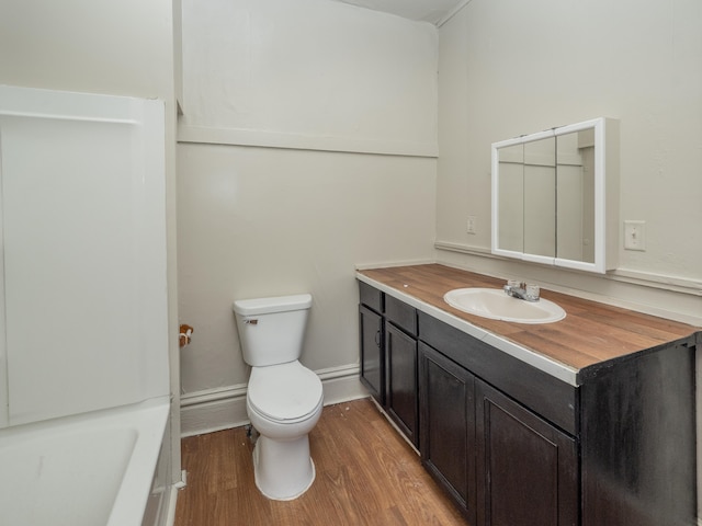 bathroom featuring a washtub, vanity, wood-type flooring, and toilet