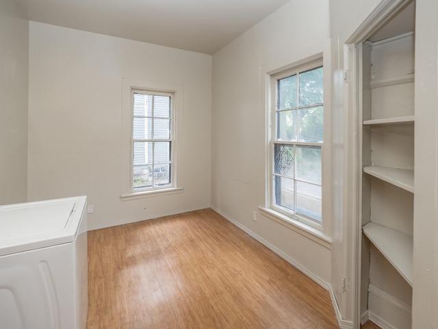 clothes washing area featuring washer / clothes dryer, a wealth of natural light, and light hardwood / wood-style flooring