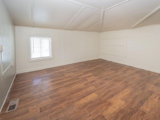 spare room featuring dark hardwood / wood-style floors and lofted ceiling