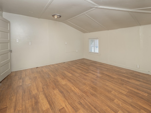 empty room with hardwood / wood-style floors and lofted ceiling