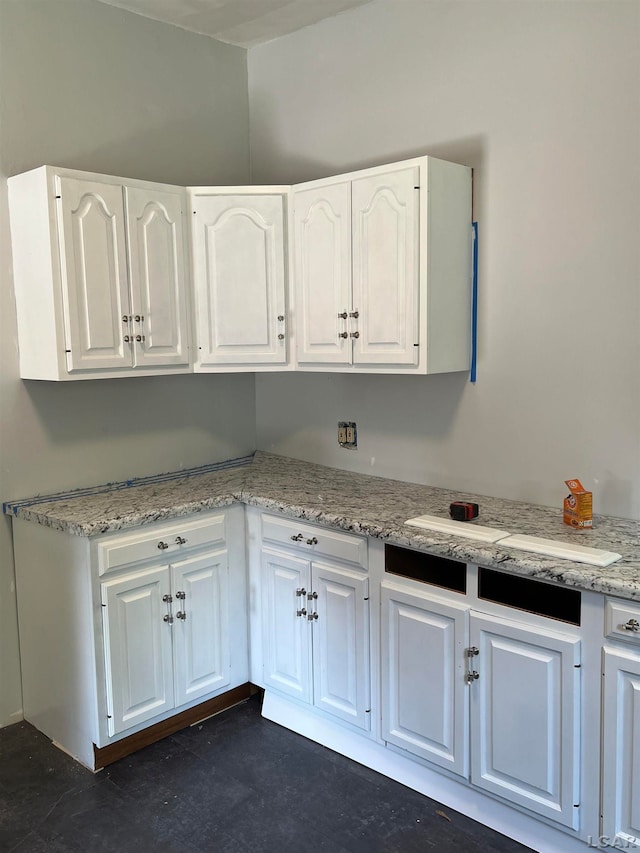 kitchen with light stone countertops and white cabinetry