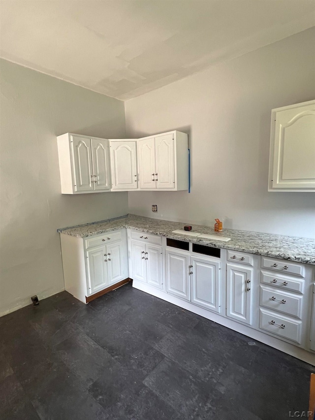 kitchen featuring white cabinetry, sink, and light stone counters