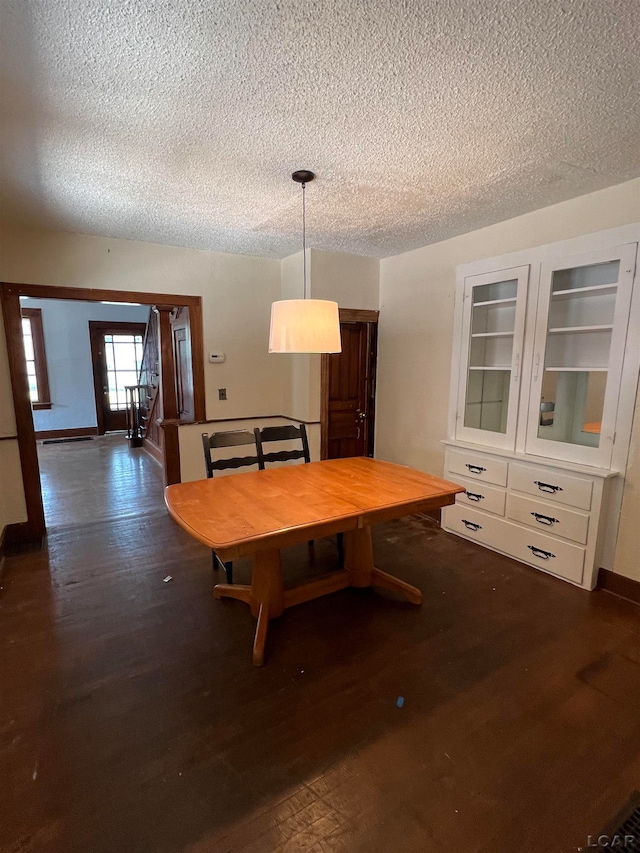 unfurnished dining area with a textured ceiling and dark wood-type flooring