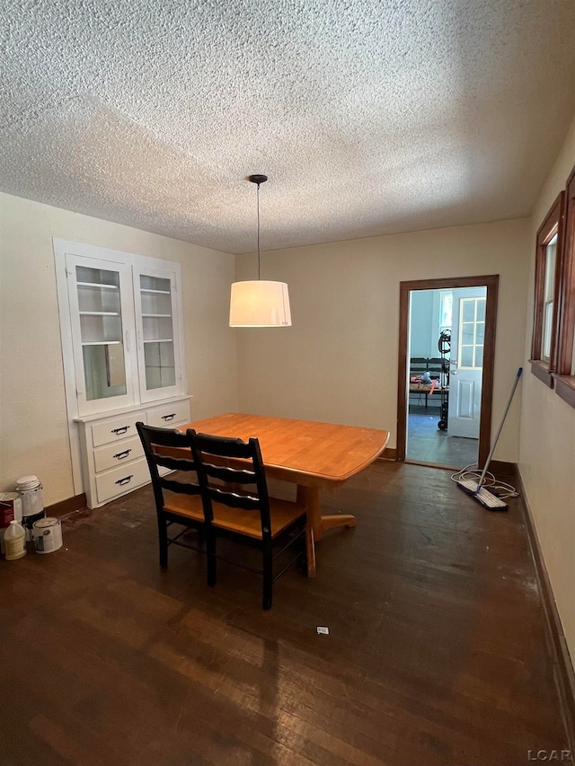 dining room featuring a textured ceiling and dark hardwood / wood-style floors