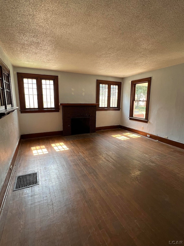 unfurnished living room with a wealth of natural light, wood-type flooring, and a textured ceiling