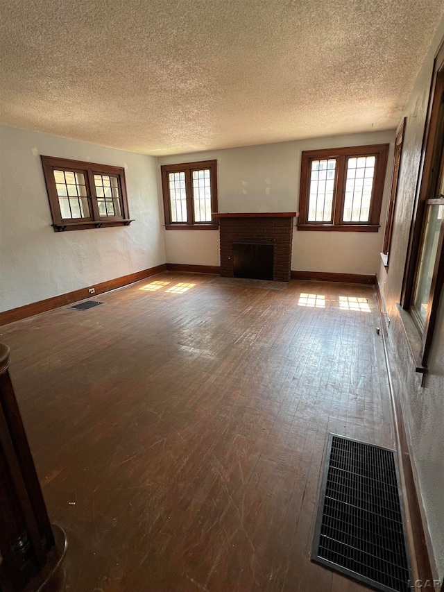 unfurnished living room with wood-type flooring, a textured ceiling, and a wealth of natural light