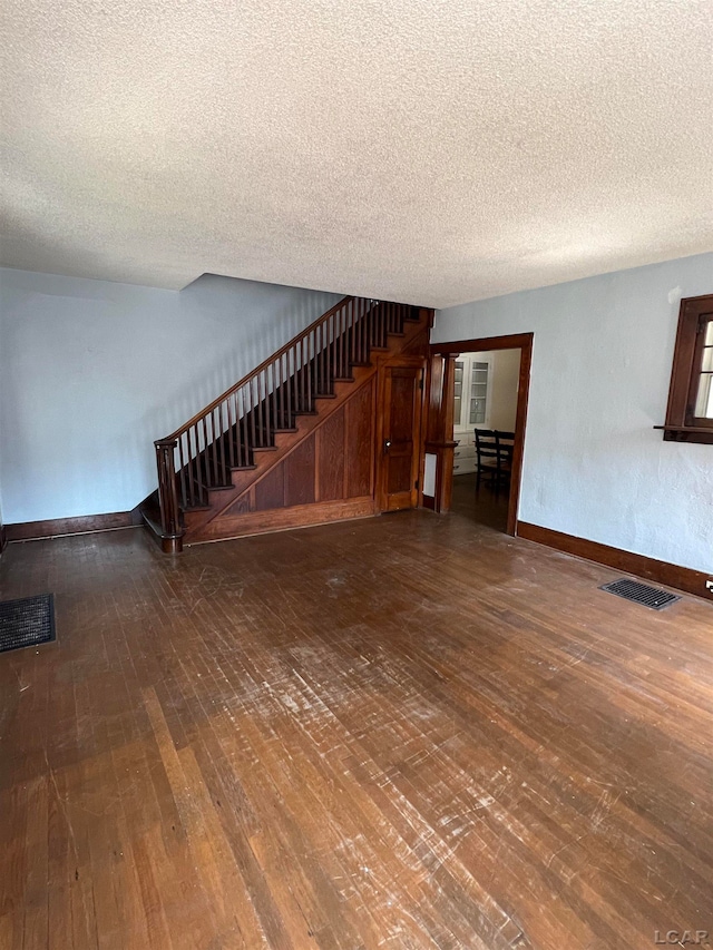 unfurnished living room with a textured ceiling and dark wood-type flooring