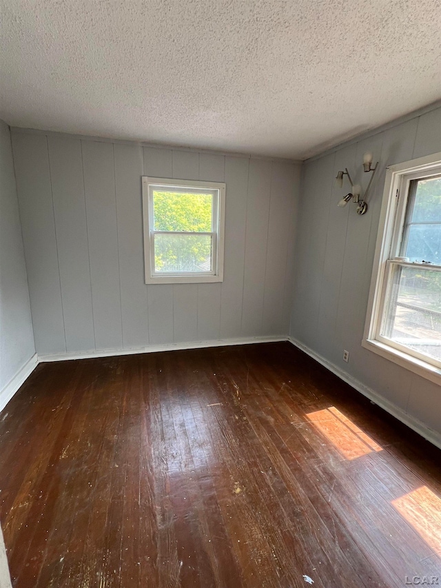 empty room featuring a textured ceiling and dark wood-type flooring