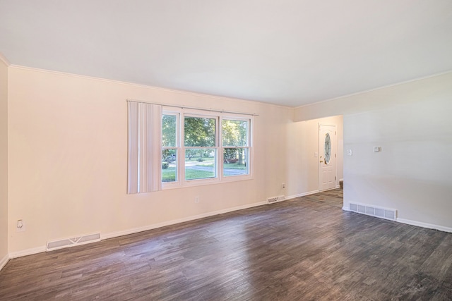 spare room featuring dark wood-type flooring and ornamental molding