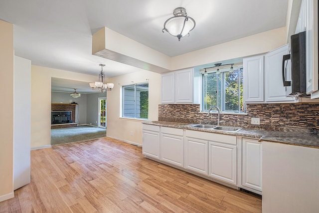 kitchen with white cabinets, pendant lighting, light wood-type flooring, and sink