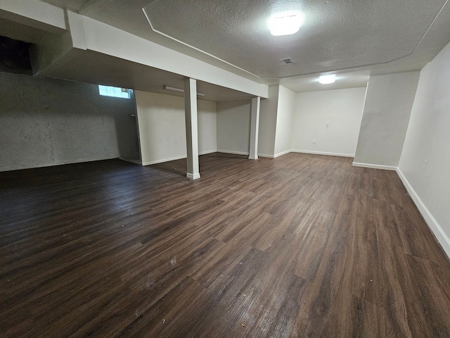 basement with a textured ceiling and dark hardwood / wood-style flooring