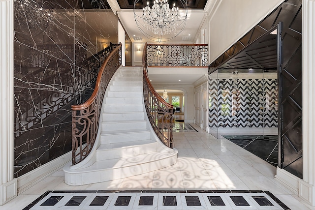 foyer with tile patterned flooring, an inviting chandelier, and ornamental molding