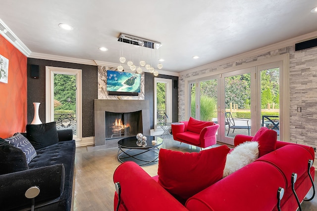 living room featuring hardwood / wood-style floors, crown molding, a high end fireplace, and french doors