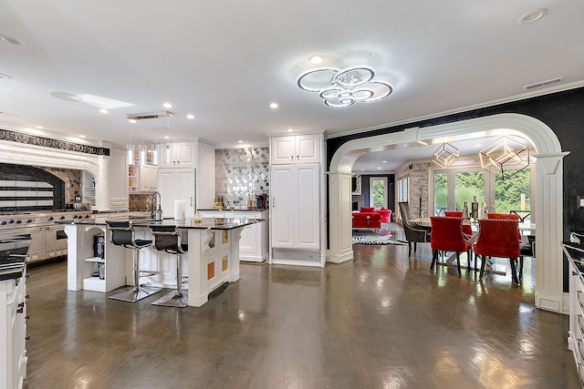 kitchen with white cabinets, a kitchen breakfast bar, a kitchen island with sink, and dark wood-type flooring