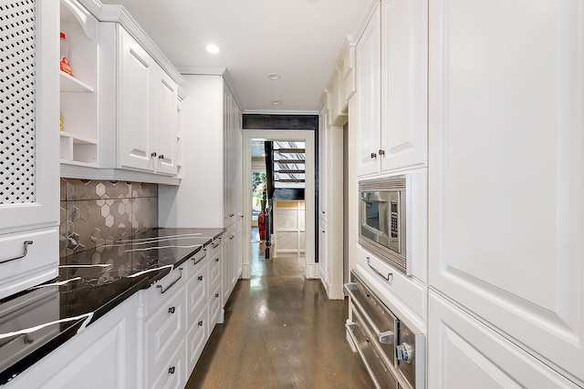 kitchen with dark hardwood / wood-style flooring, stainless steel microwave, white cabinetry, and backsplash