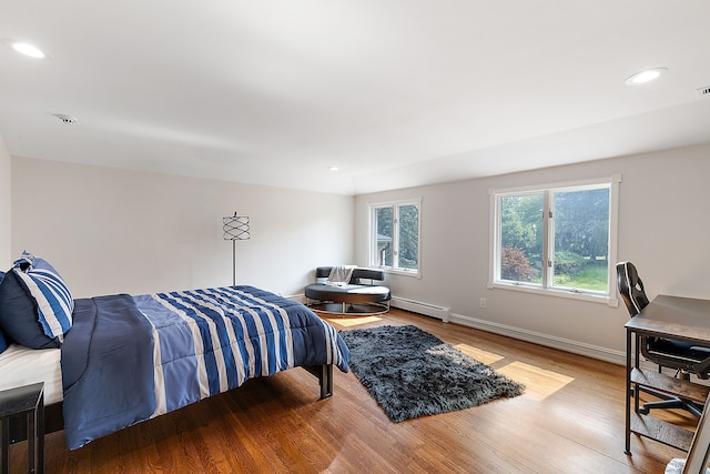 bedroom with light hardwood / wood-style floors and a baseboard heating unit