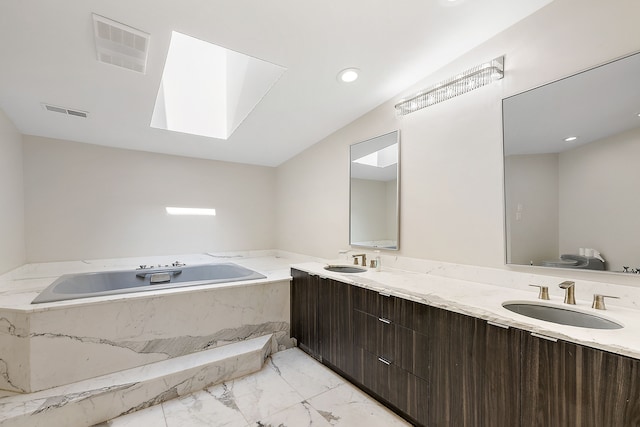 bathroom with tiled bath, a skylight, vanity, and toilet