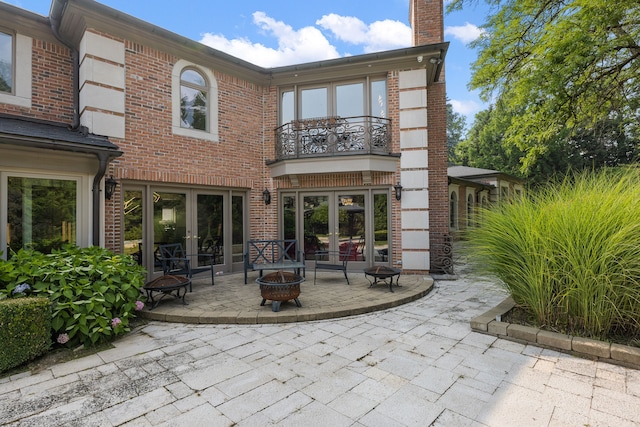 back of house with a patio area, a balcony, an outdoor fire pit, and french doors