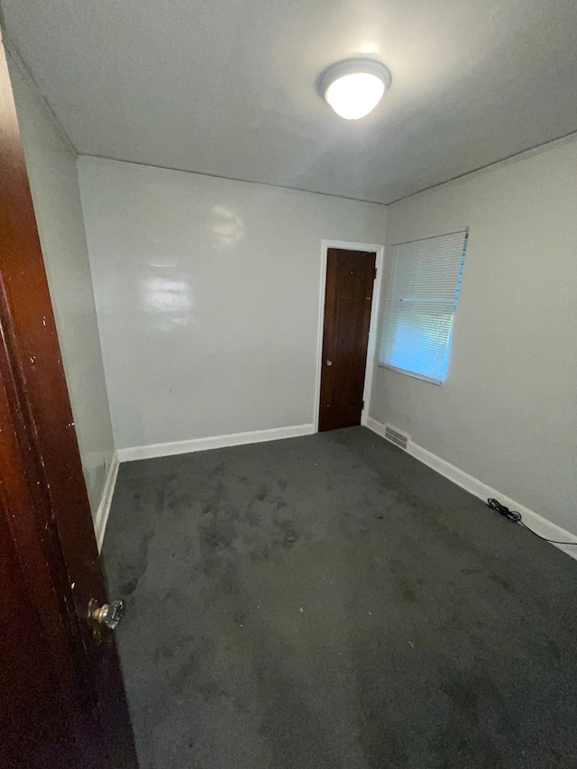 spare room featuring dark carpet