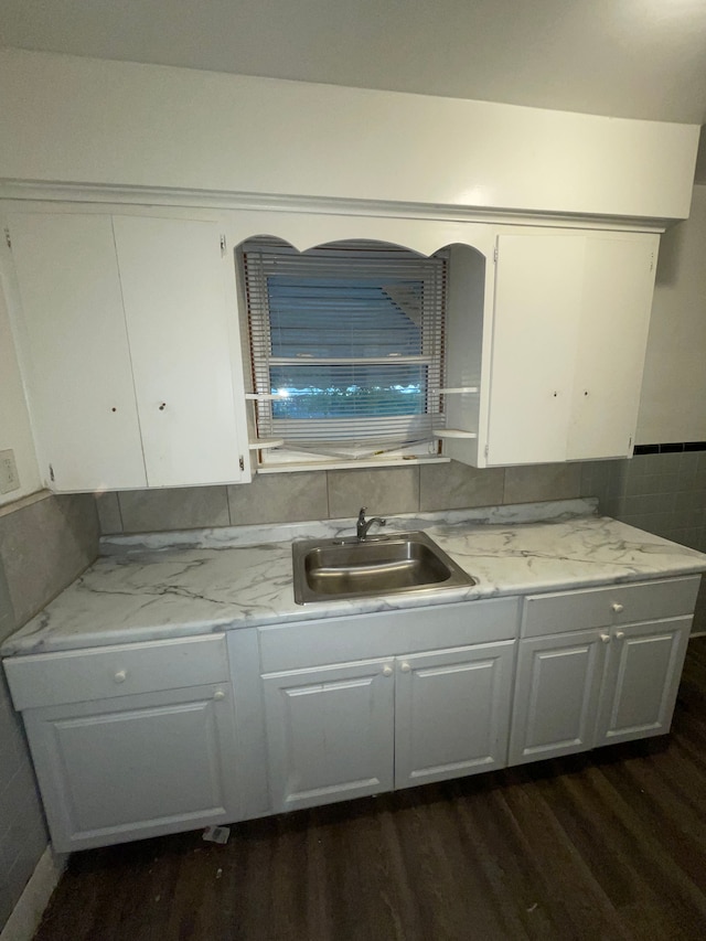 kitchen with light stone counters, sink, white cabinets, and dark hardwood / wood-style floors