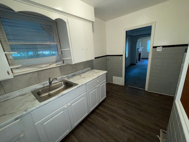 kitchen with light stone countertops, sink, tile walls, dark hardwood / wood-style floors, and white cabinetry