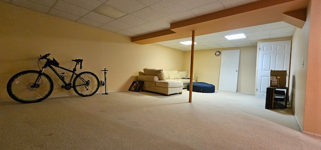 basement featuring a paneled ceiling and light carpet