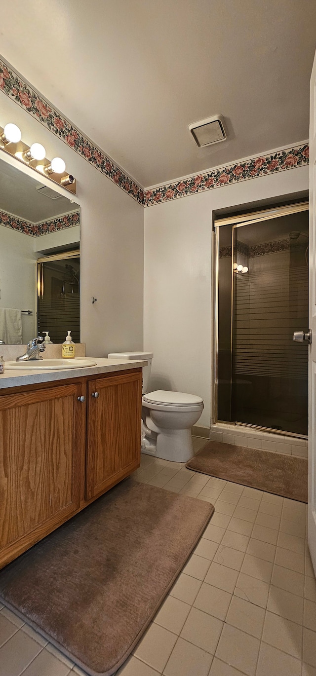 bathroom featuring tile patterned floors, vanity, toilet, and walk in shower