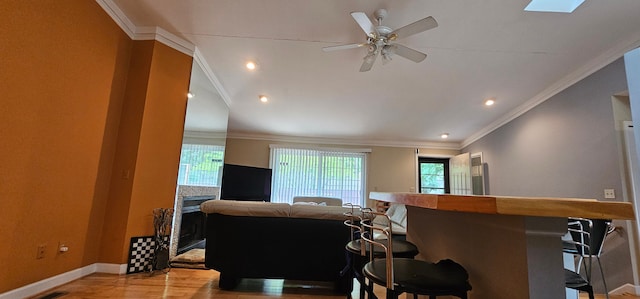 living room with hardwood / wood-style flooring, ceiling fan, ornamental molding, and vaulted ceiling